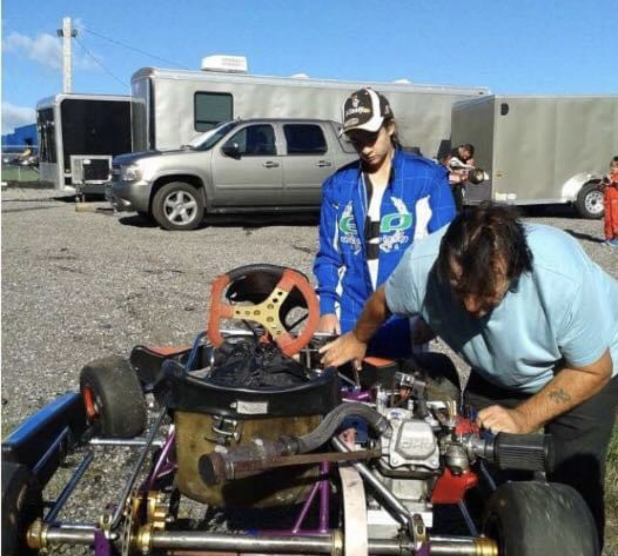Female racer watches as her mechanic tunes her racing kart